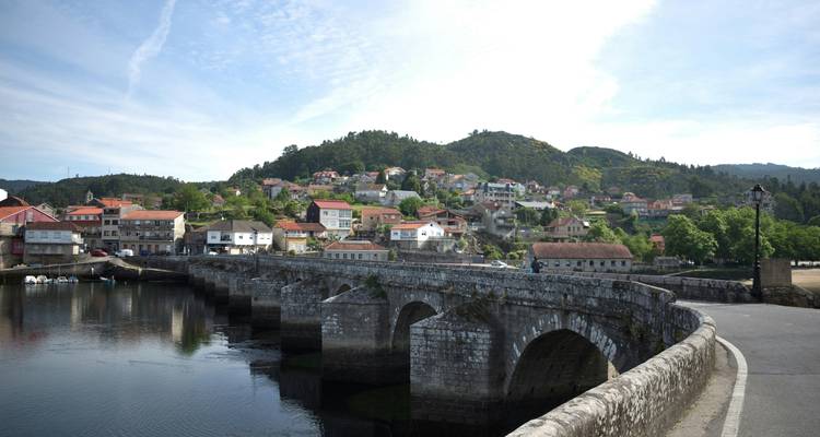 Alte Steinbrücke, die zu einem kleinen Dorf führt.