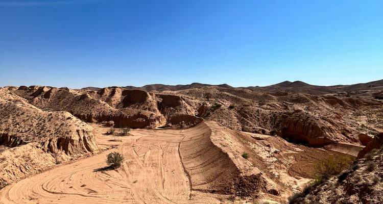 Paisaje árido con colinas erosionadas bajo un cielo azul despejado.