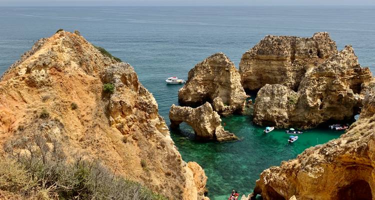 Dramatische Küstenklippen mit blauem Meer und Booten.