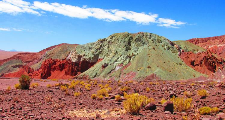 Kleurrijke rotsformaties met rode en groene tinten in een woestijnlandschap.