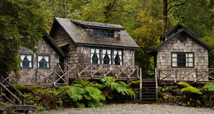 Cabanes rustiques en bois entourées d'un feuillage vert luxuriant.