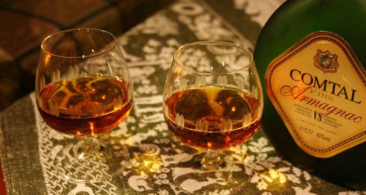 Deux verres d'Armagnac et une bouteille sur une table.