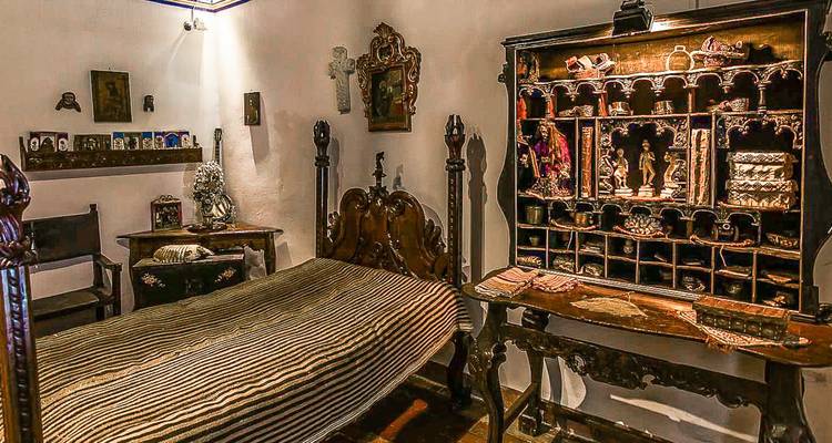 Interior of a historic room with antique furniture and religious artifacts.