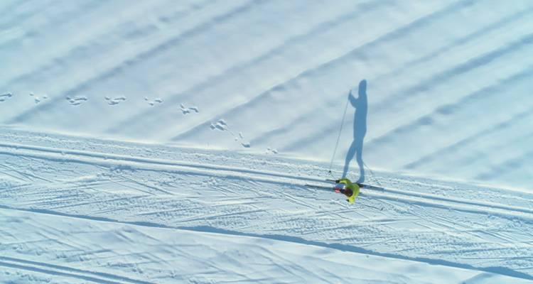 Vue aérienne d'un skieur sur un large champ enneigé avec une ombre.