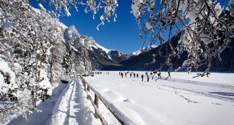 Des personnes profitant d'activités de neige près d'un lac gelé avec un paysage de montagne en arrière-plan.