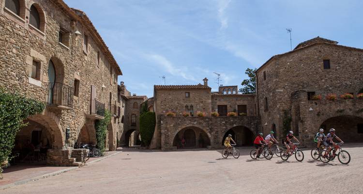 Des cyclistes traversant une place de ville historique avec une architecture en pierre.