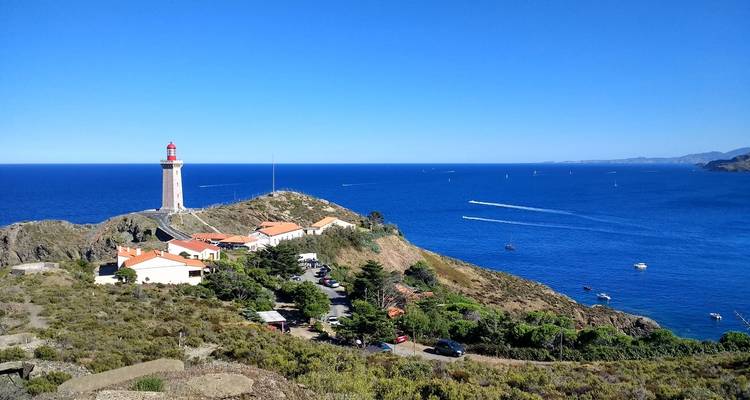 Phare sur une péninsule rocheuse avec une mer et un ciel bleu clair.