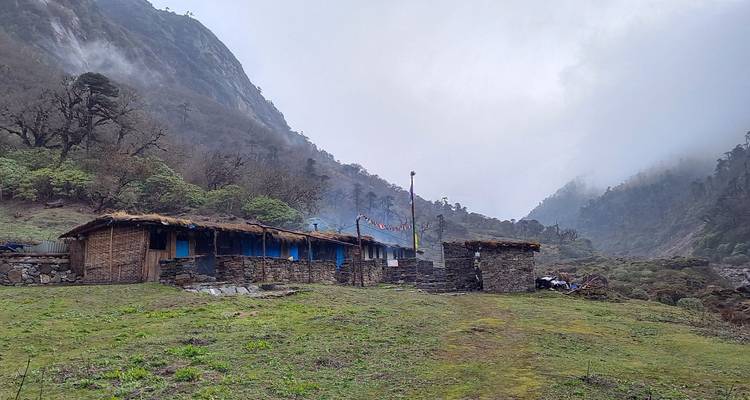Afgelegen bergdorp met bescheiden bouwwerken genesteld in een mistige vallei.