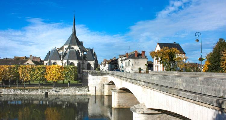 Église et pont sur une rivière, entourés de bâtiments.