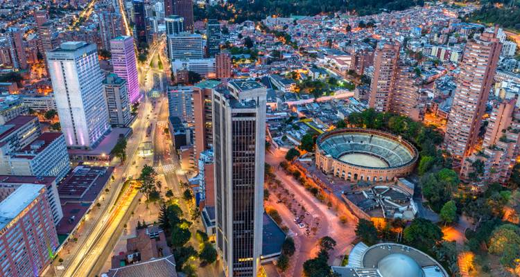 An aerial cityscape featuring busy streets, high rises, and a bullring at dusk.