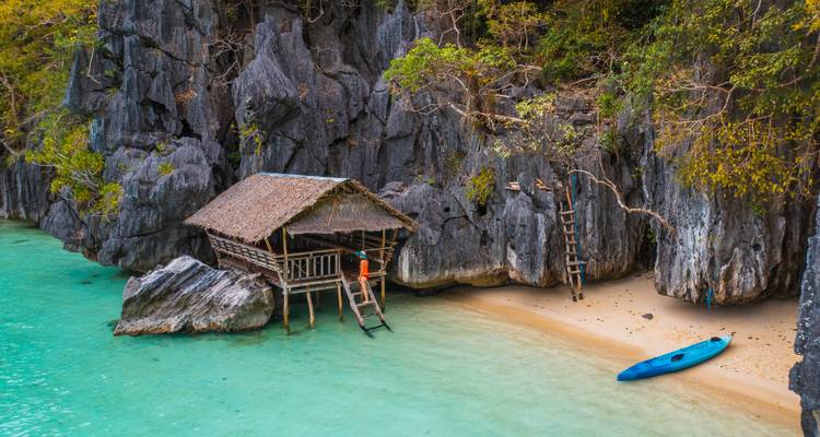 Rustikale Hütte an einem Korallenstrand mit klarem Wasser.