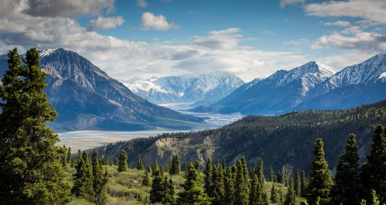 A breathtaking view of a valley surrounded by tall snow-covered mountains.