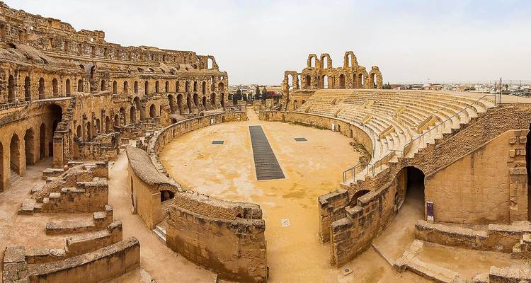 Amphithéâtre antique avec sol sablonneux et structures voûtées.