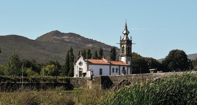 Picturesque church with stone architecture and a backdrop of hills.