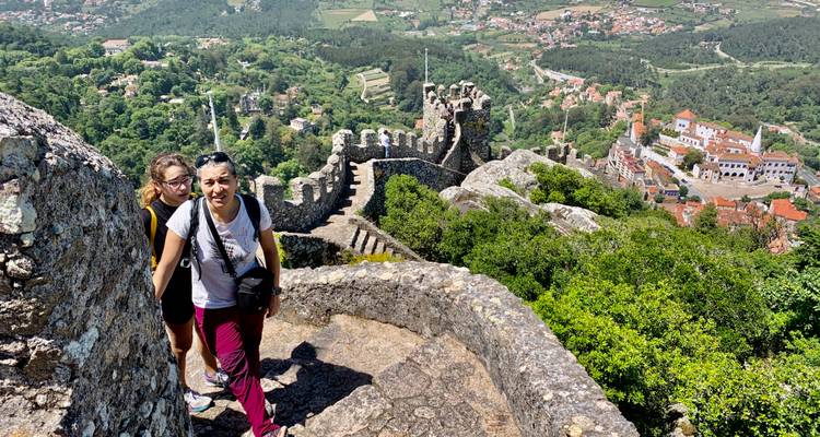 Tourists exploring ancient castle ruins overlooking a valley