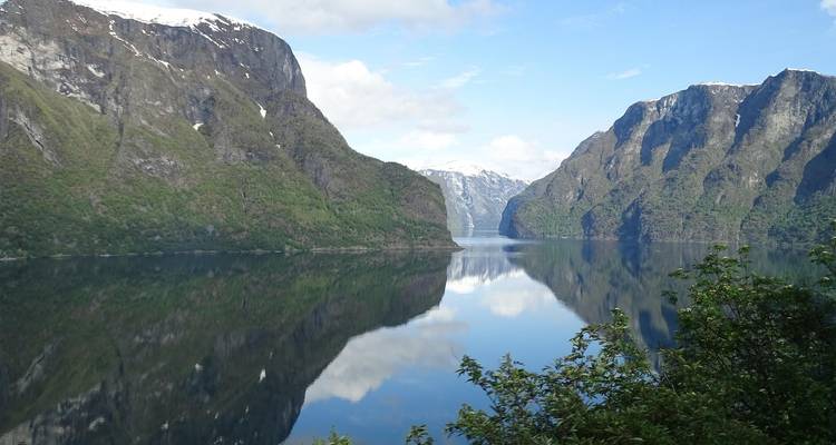 Des montagnes enneigées se reflétant dans un fjord.