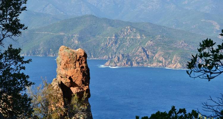 Vue large des montagnes et d'un affleurement rocheux surplombant la mer.