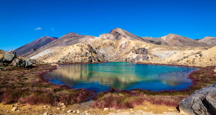 Kleurrijk meer omgeven door bergachtig terrein.