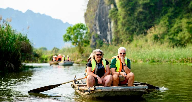 Tourists in a small boat on a calm river with lush surroundings.