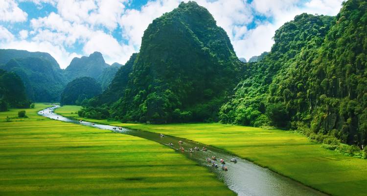Scenic river winding through lush green fields in a karst landscape.