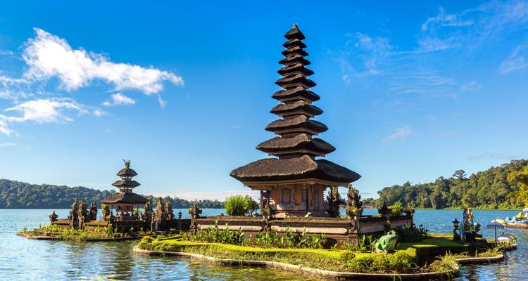 Pagoda-style temple on water with mountains in the background.