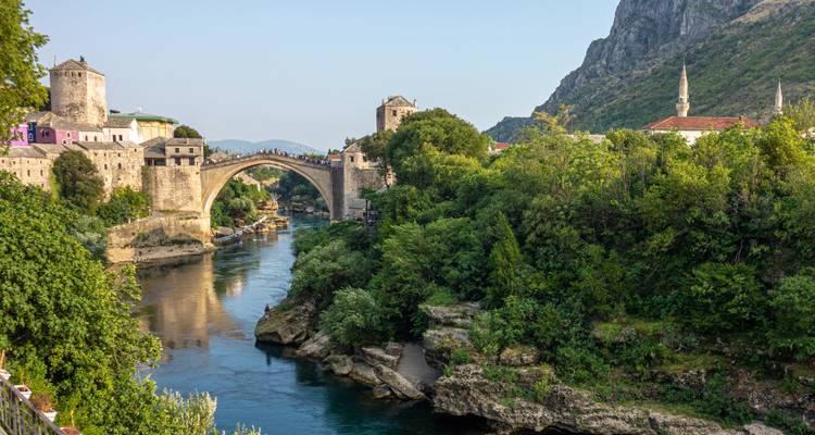 Pont historique en pierre sur une rivière entouré d'une végétation luxuriante.