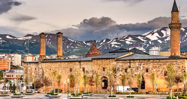 Historisches Gebäude mit schneebedeckten Bergen im Hintergrund.