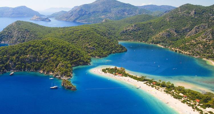 Aerial of the turquoise lagoon and curved sandy spit of Ölüdeniz backed by forested hills.