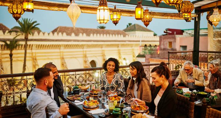 Eetscène met een groep mensen op een dakterras met traditionele lantaarns.