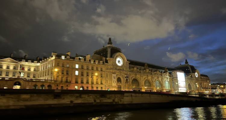 Bâtiment de gare illuminé la nuit avec des nuages au-dessus.