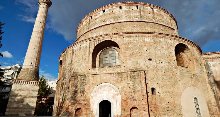 A round brick building with a tall minaret under a vibrant sky.