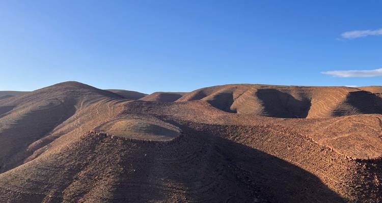 Collines désertiques sous un ciel bleu éclatant.