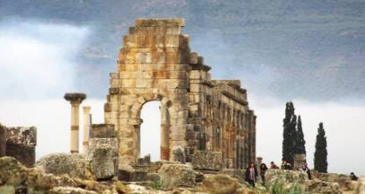 Ruines anciennes avec une arche et des arbres en arrière-plan.