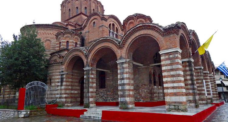 A historic brick church with arched entrances and flags.