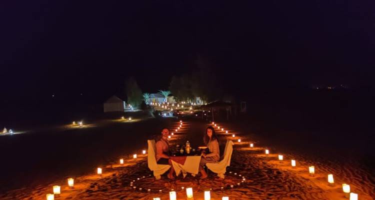 Romantic candlelit dinner setup in the desert at night.