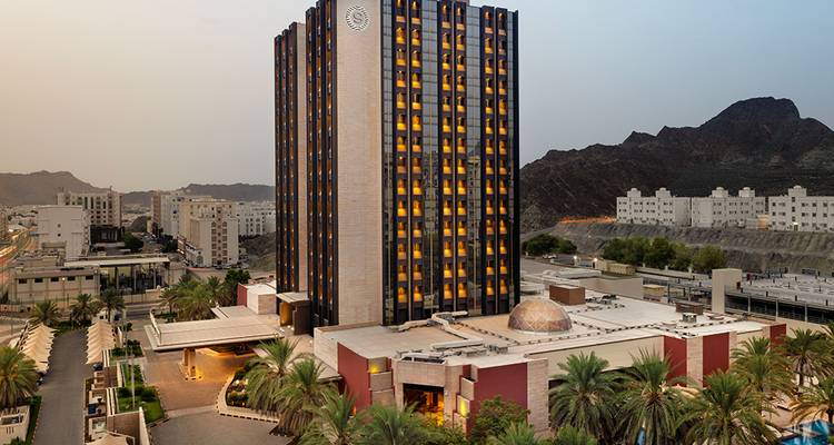 Grand bâtiment d'hôtel avec des montagnes en arrière-plan au crépuscule.