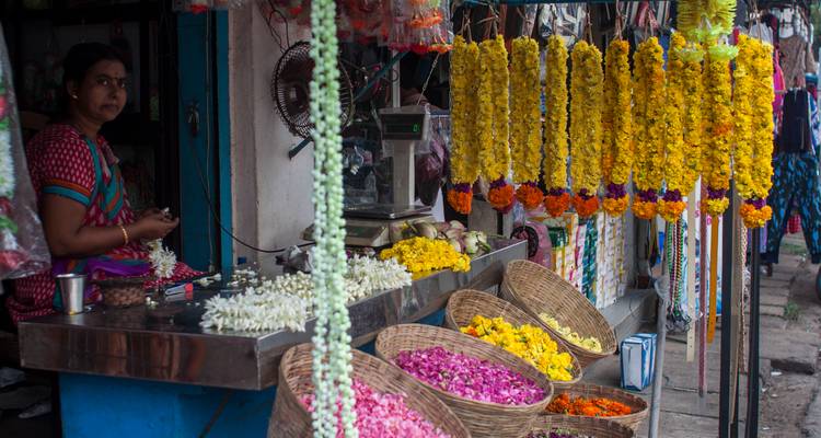 Flower market with colorful garlands and a vendor.