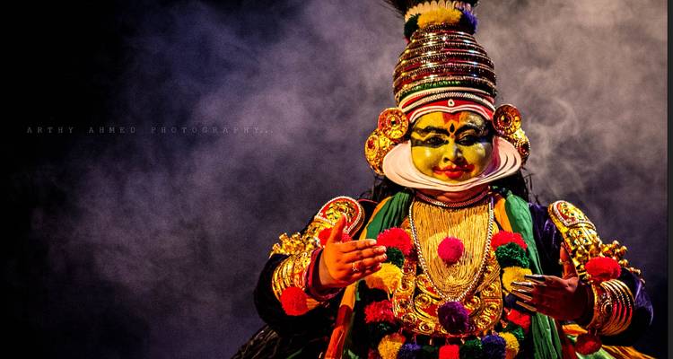 Traditional dance performer in elaborate costume with a watermark.