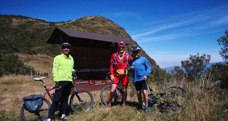 Trois cyclistes posant avec leurs vélos sur un sentier entouré de collines.