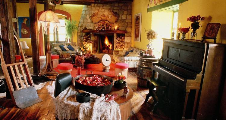 Intérieur chaleureux avec une cheminée, un piano et un mobilier rustique.