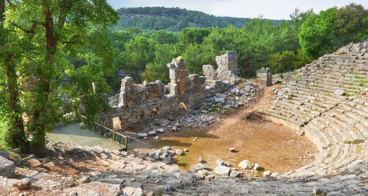 Stenen resten van een oud amfitheater op een heuvel omringd door dicht groen bos in de provincie Antalya.