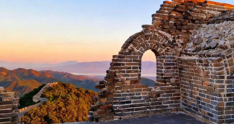 View from the Great Wall of China showing ancient brickwork against a sunrise.