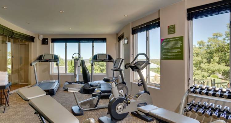 Intérieur de salle de sport avec équipements d'exercice et grandes fenêtres.