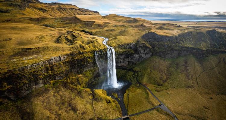 Una cascada cayendo por un acantilado hacia un valle exuberante.