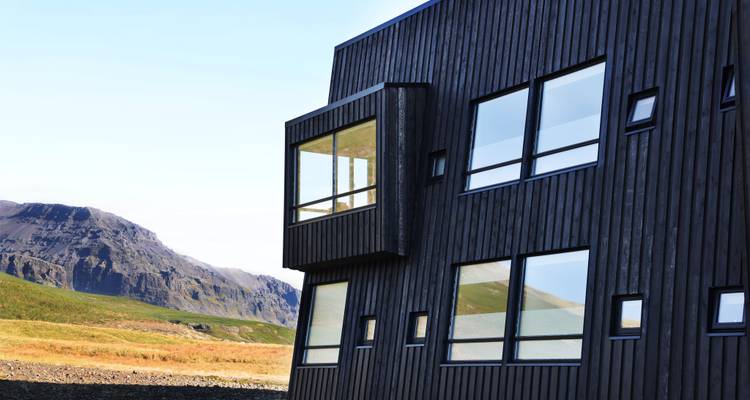Un edificio moderno con grandes ventanas situado contra un paisaje montañoso.