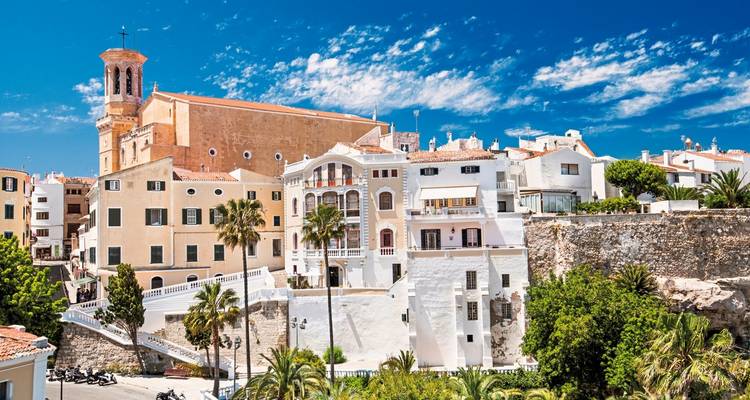 Whitewashed buildings with a large church against a bright blue sky.