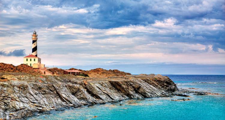 Lighthouse on a rocky coastline with moody skies.