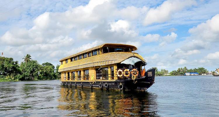 Une péniche sur un lac calme avec un ciel bleu et des arbres en arrière-plan.