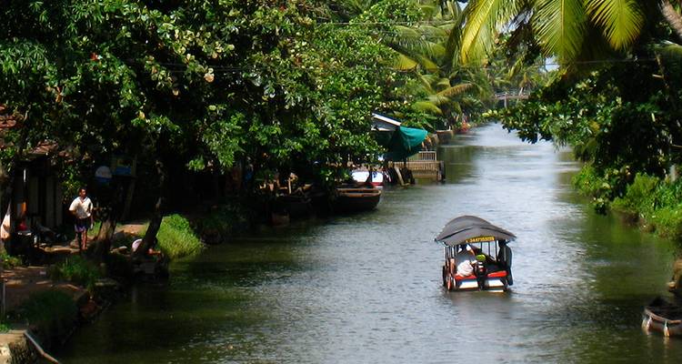 Petit bateau sur un canal étroit entouré d'une végétation luxuriante.