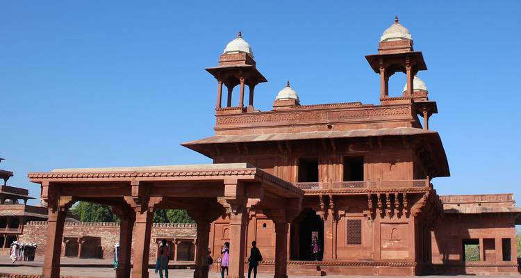 Historical red sandstone building with people passing by